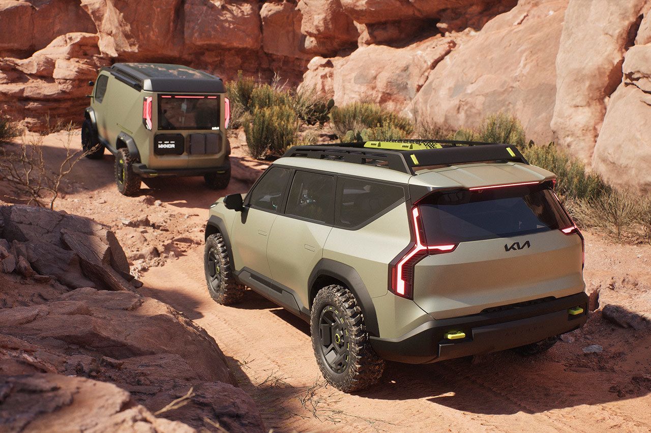 Kia EV9 "ADVNTR" concept vehicle driving on rocky terrain behind the Kia PV5 "WKNDR" concept vehicle in the desert