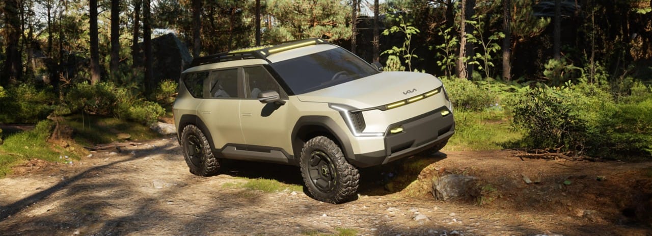 Kia EV9 "ADVNTR" concept vehicle in a three-quarter view, parked over a large rock in the mountains