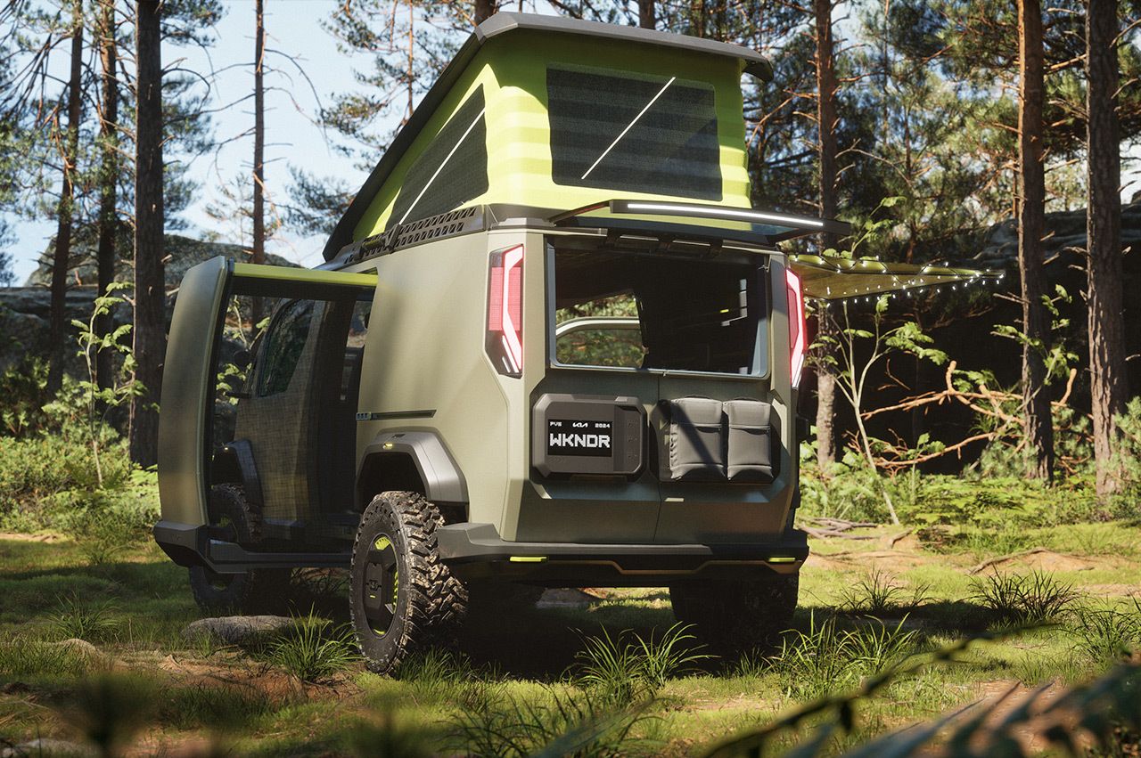 Kia "WKNDR" concept EV van in the middle of a forest showcasing its flexible modular interior to store camping equipment in its gear head, rear three-quarter view