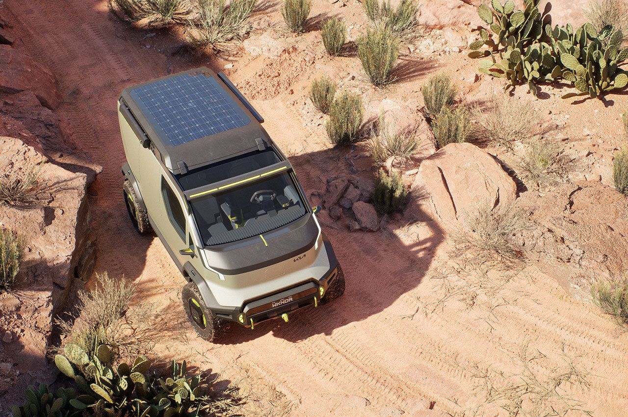 Kia "WKNDR" concept EV van driving through rugged terrain in the desert, bird's eye view