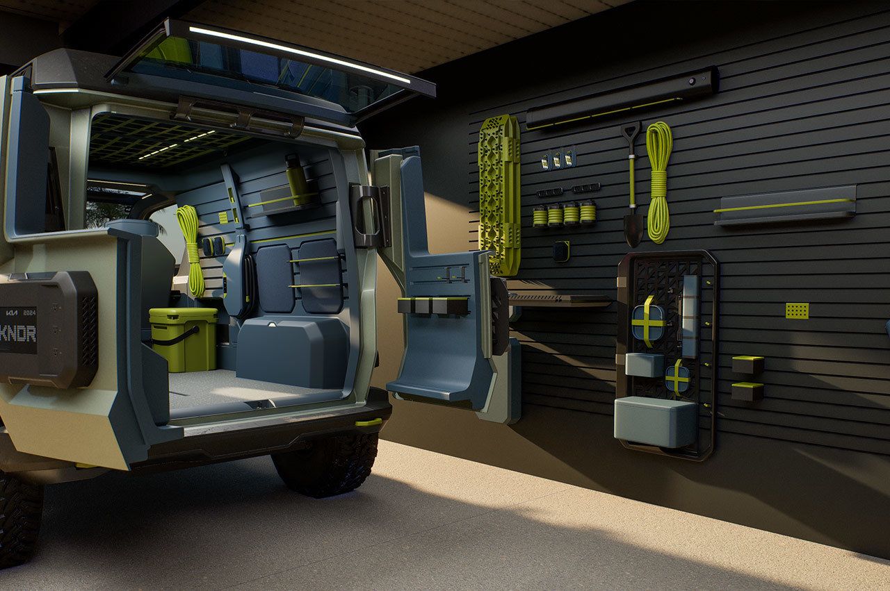 Kia "WKNDR" concept EV van parked in the owner's garage full of tools, with the rear trunk opened to highlight its spacious cargo area, rear three-quarter view