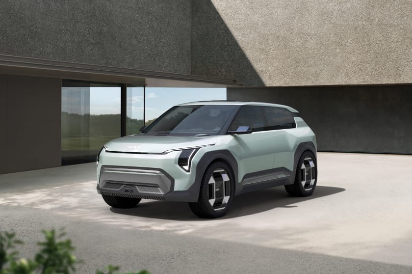 Prototipo del Kia EV3 en verde claro en una vista frontal de tres cuartos, estacionado delante de un edificio moderno.