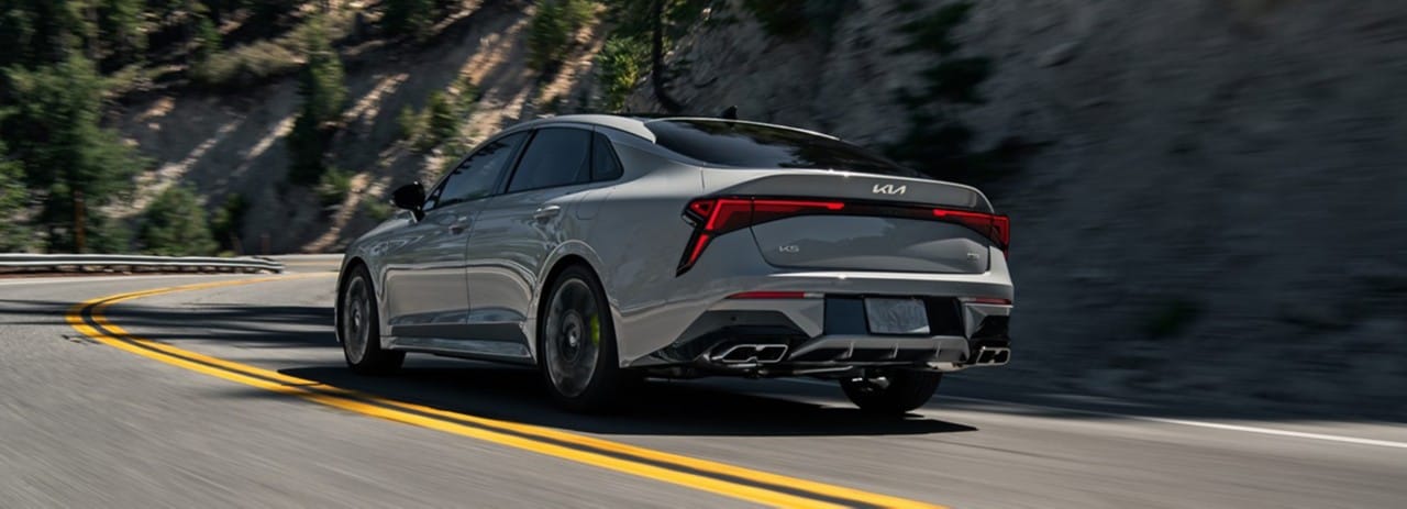 Vista trasera de tres cuartos del Kia Stinger 2023 conduciendo rápido y haciendo un giro cerrado en una pista de carreras vacía