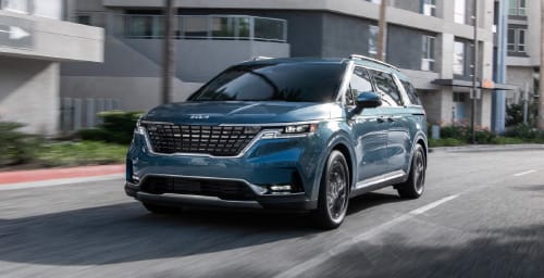 Kia vehicle in blue, three-quarter front view, driving down a residential road